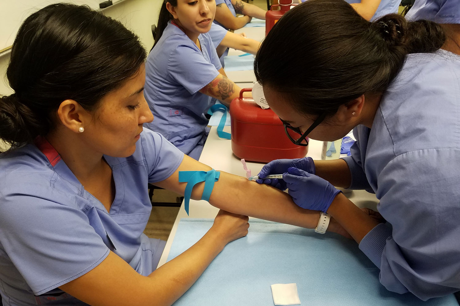 A medical assisting professor helps a student during a lab course.